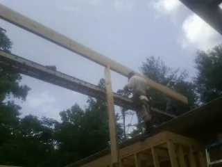 Carpenter setting a ridge beam over a new addition frame — Ice Dam Removal by Roofing Brothers in Glenoma