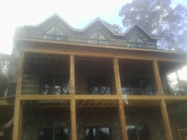 Dormers and porch framing on a large log home under construction — Roof Coating work by our crew in Glenoma