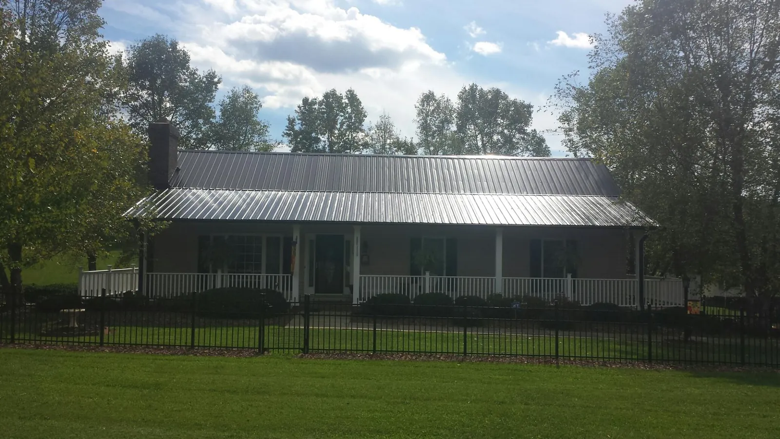 Gray metal roof on a brick ranch with a full width front porch — Gutter Guard Installation work by our crew in Glenoma