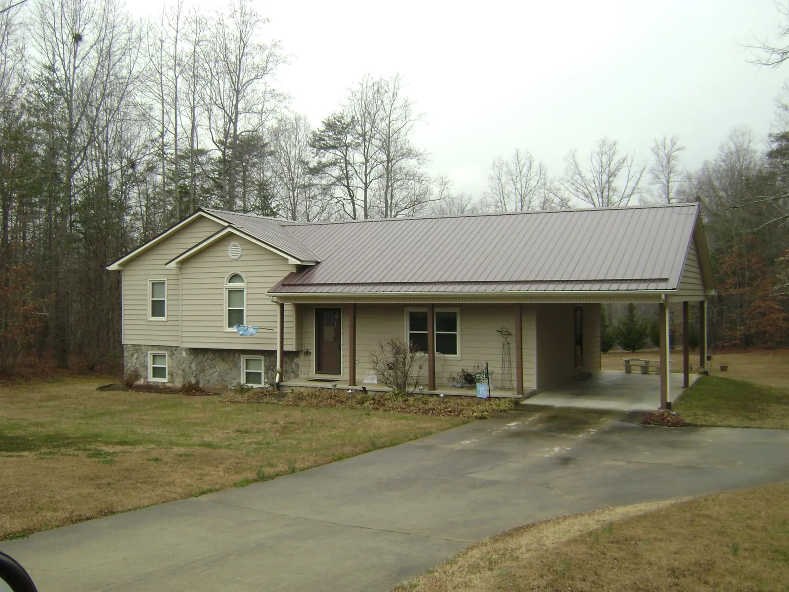 Brown metal roof on a tan split level home with an attached carport in Glenoma