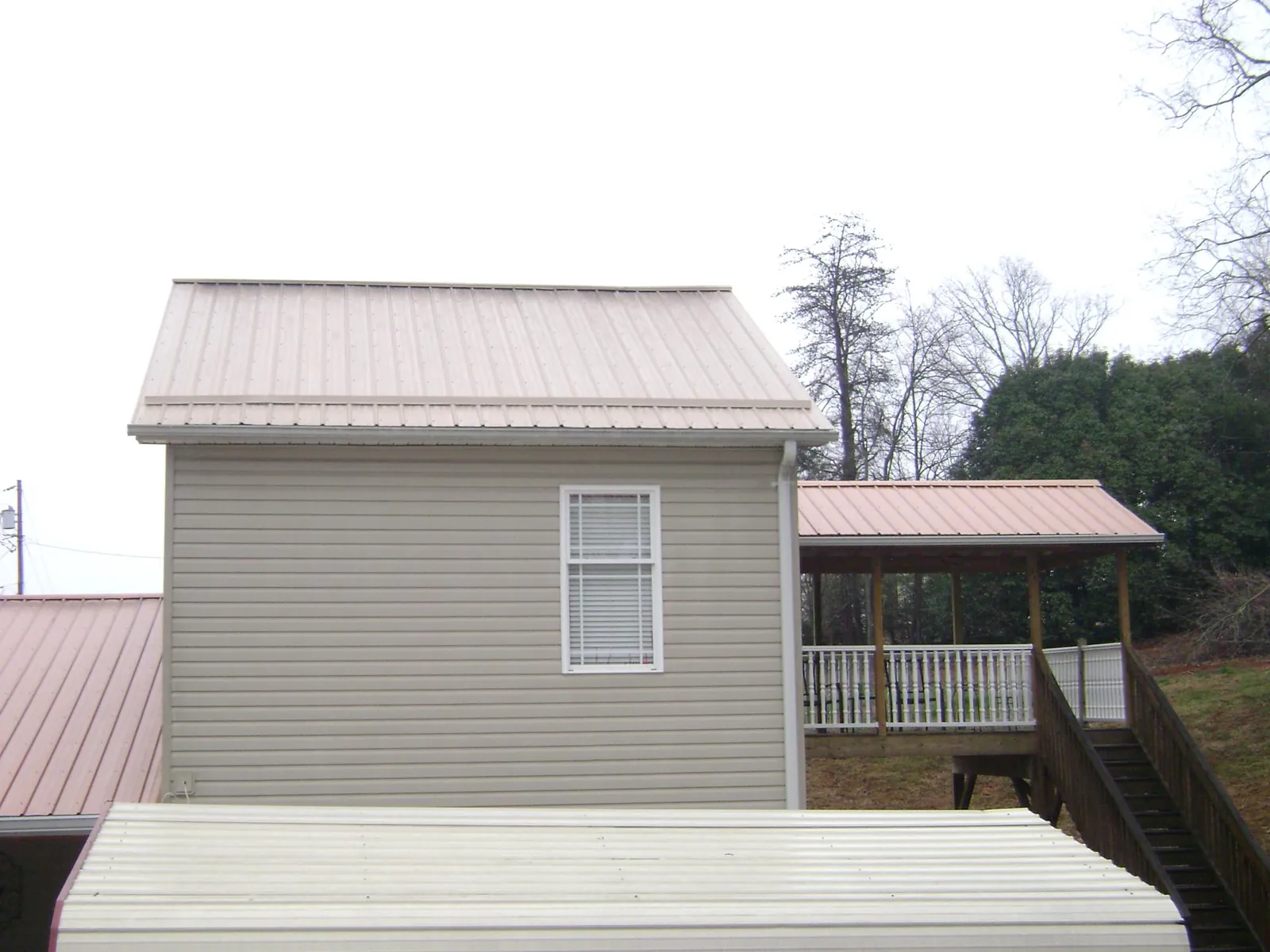 Tan metal roofs on a two story addition and attached porch, from a Roof Replacement job in Glenoma