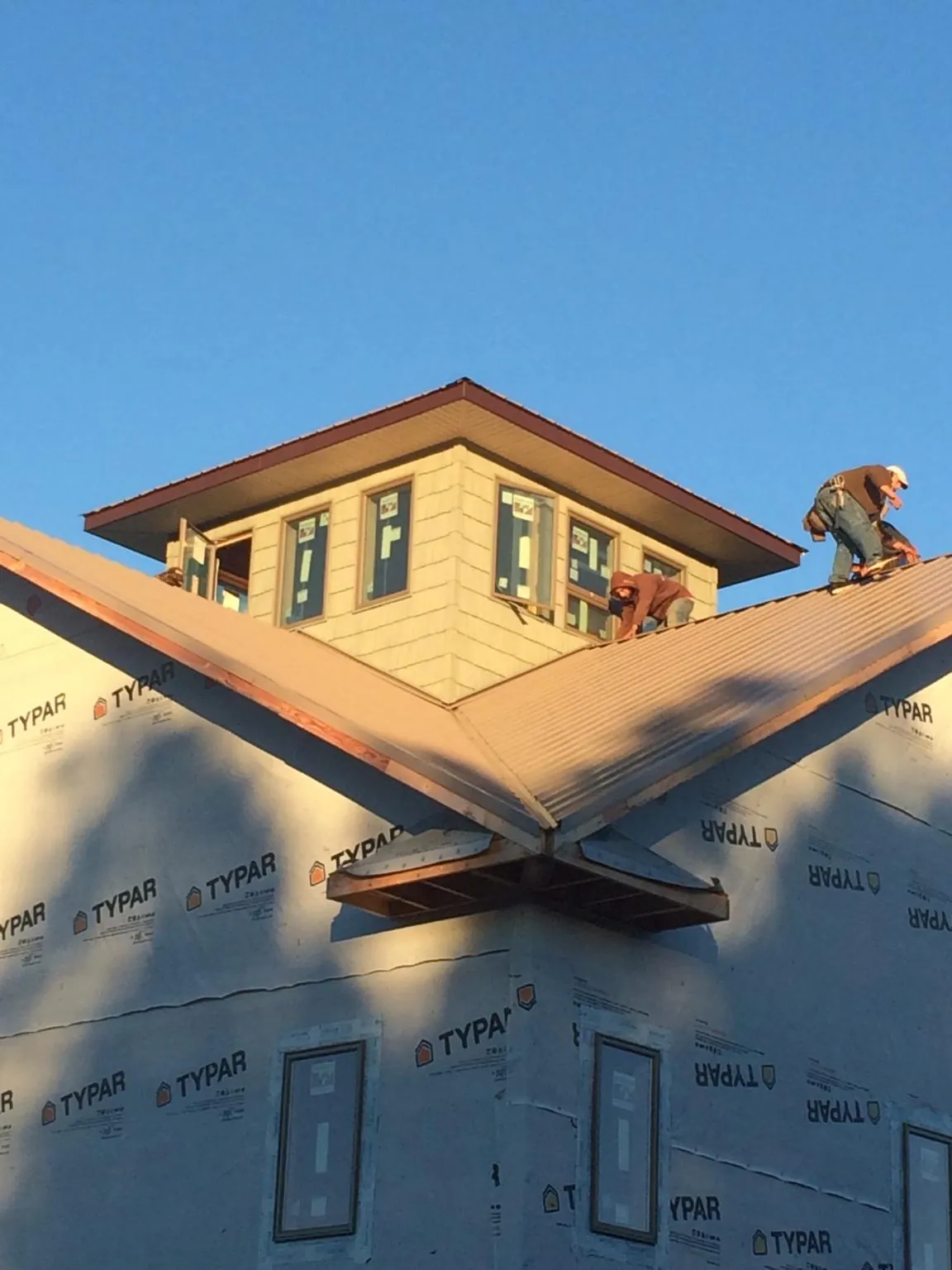 Roofers working around a rooftop cupola on a new metal roof at sunset — Roof Waterproofing in Glenoma by Roofing Brothers